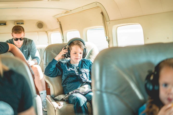 Little boy putting on headphones inside plane